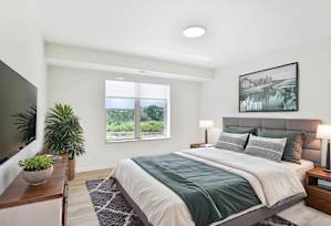 A bedroom with a large bed, a nightstand, and a painting on the wall.