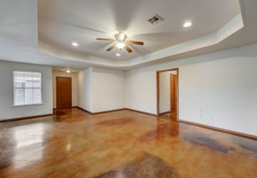 an empty living room with a ceiling fan and a window