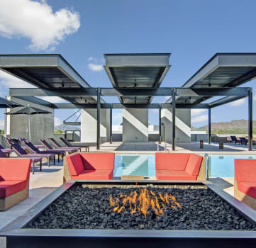 a lounge area with couches and chairs around a fire pit