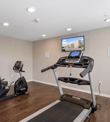 a home gym with two treadmills and a flat screen tv
