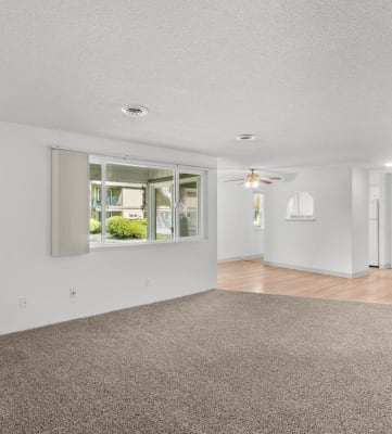 a spacious living room with white walls and carpet