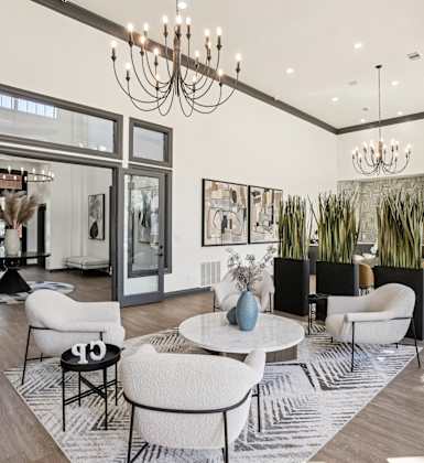 A modern living room with a white sofa set and a chandelier.
