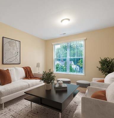 A living room with a white couch, a coffee table, and a small potted plant.