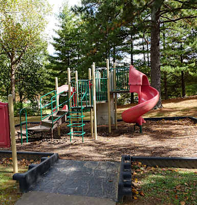 a playground with a red slide in a park