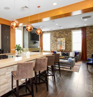 a kitchen with a large center island with a breakfast bar and a living room in the background