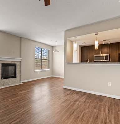 a living room with a fireplace and a kitchen in the background
