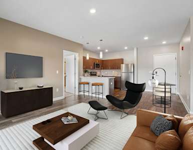 A modern living room with a brown sofa, a wooden coffee table, and a flat-screen TV mounted on the wall.