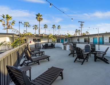 A patio with chairs and a table is surrounded by palm trees at Ocean Breeze Terrace Apartment, Huntington Beach