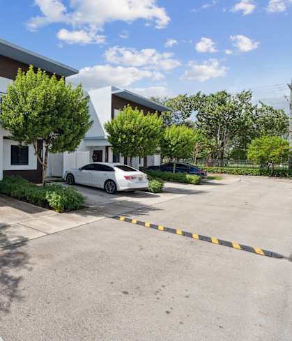 A white car is parked in a driveway in front of a house.at The Villages at Miami Gardens, Florida, 33056