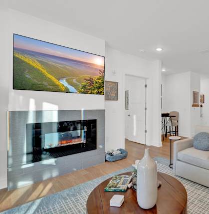 A modern living room with a fireplace and a large TV on the wall.