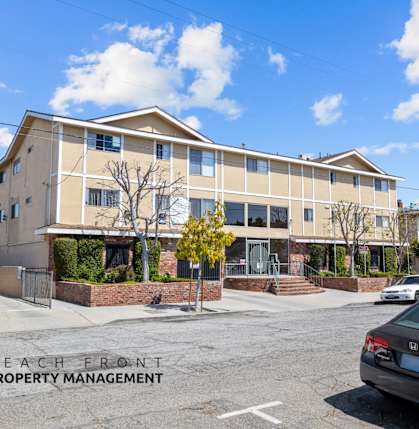A car is parked in front of a multi-story building with the words "Beach Front Property Management" on the bottom left.