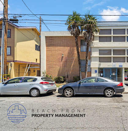 A car dealership with a sign that says "Now Leasing" is in front of a building with a palm tree.