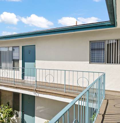 A balcony with a metal railing and a blue door.