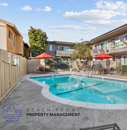 A pool surrounded by a fence and a bench with the words Beach Front Property Management.