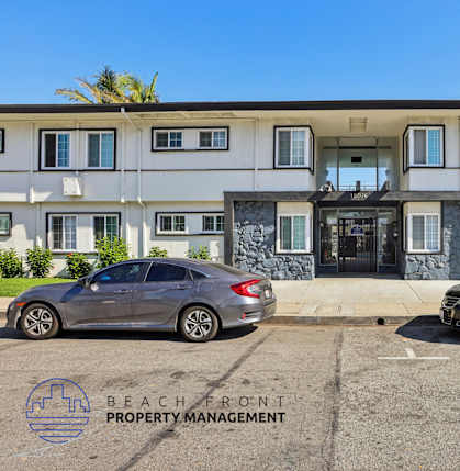 Two cars are parked in front of a building with the logo "BEACH FRONT PROPERTY MANAGEMENT" on the ground.