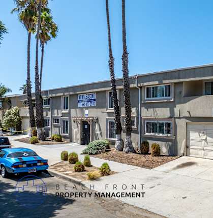 A blue car is parked in front of a building with the sign "BEACH FRONT PROPERTY MANAGEMENT".
