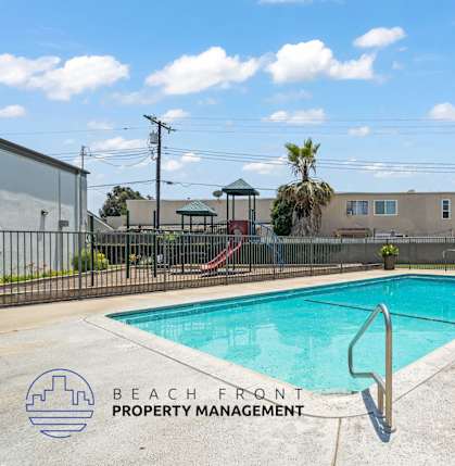 A pool with a slide and a building in the background.