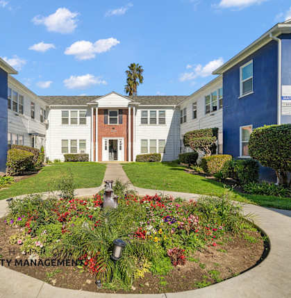 A garden in front of a building with the logo of Beachfront Property Management.