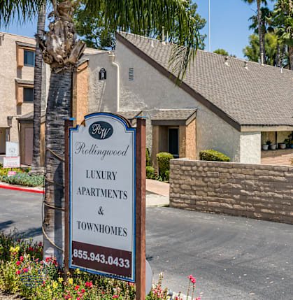 A sign for luxury apartments and townhomes stands in front of a building.