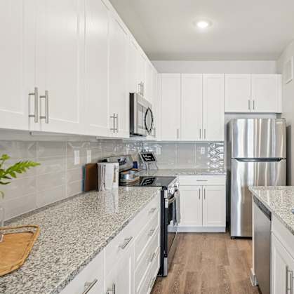 A kitchen with white cabinets and a granite countertop.