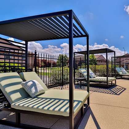A poolside area with sun loungers and a metal fence.