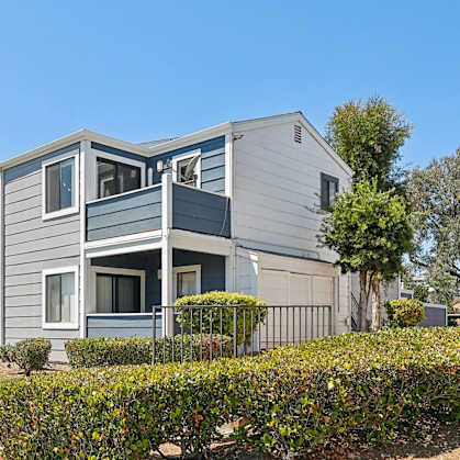 A grey and white building with a green lawn in front.