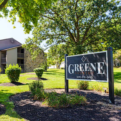 a sign that says greene apartments with a building in the background