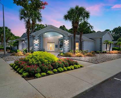 a house with a sidewalk and palm trees in front of it at St. Andrews Reserve Apartments in Wilmington, NC