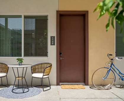 A small table with two chairs and a potted plant sits on a patio.