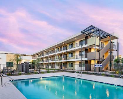 A modern apartment complex with a swimming pool in the foreground.