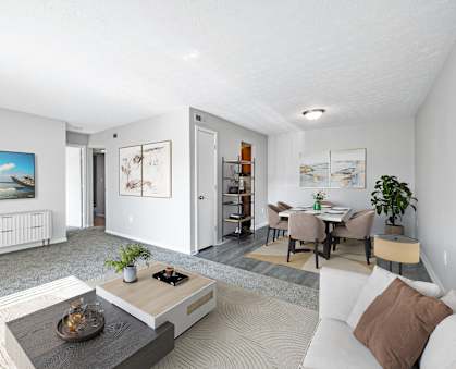 A modern living room with a white sofa, a coffee table, and a painting on the wall.