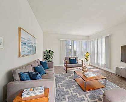 A living room with a grey couch, a wooden coffee table, and a painting on the wall.