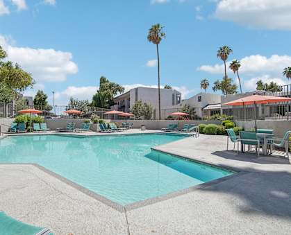 A large swimming pool with a sun lounger and umbrella.