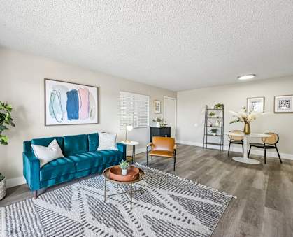 A living room with a blue couch and a grey rug.