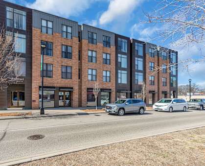 A modern brick building with a parking lot in front.