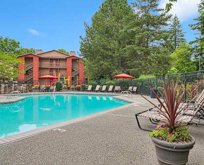 A pool area with a red umbrella and a black fence.