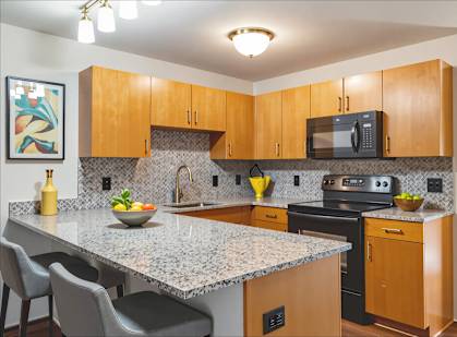 A kitchen with a granite countertop and wooden cabinets.