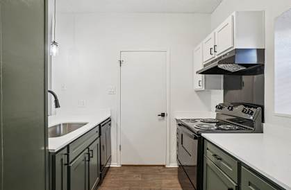 A kitchen with a white door and a stove top oven.