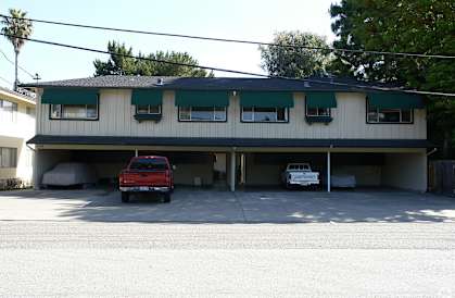 A red truck is parked in front of a two-story building.