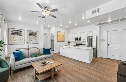 A modern living room with a white ceiling fan and a wooden coffee table.