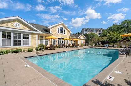 A swimming pool in front of a yellow house.