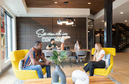 people sitting in yellow chairs in a room with a large sign on the wall