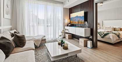 A modern living room with a large window, a sofa, a coffee table, and a bed.
