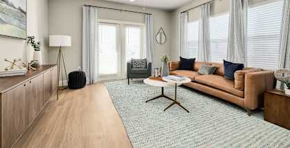 A living room with a brown couch, a white coffee table, and a wooden floor.