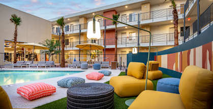 a courtyard with couches and pillows and a pool in front of a building