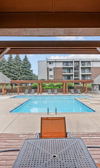 A wooden deck with a table and chairs overlooking a pool.