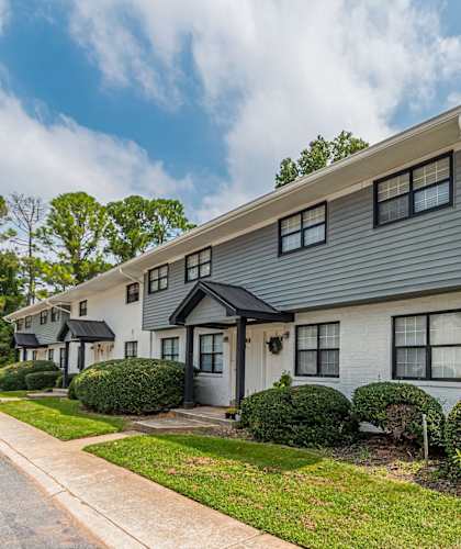 a white house with black windows and a sidewalk at Pinewood Townhomes in Tucker, GA 30084