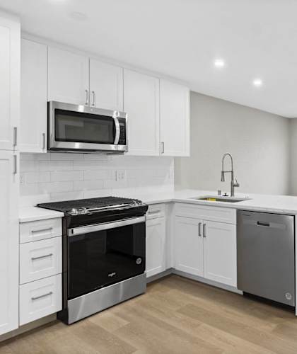 A modern kitchen with white cabinets and stainless steel appliances.