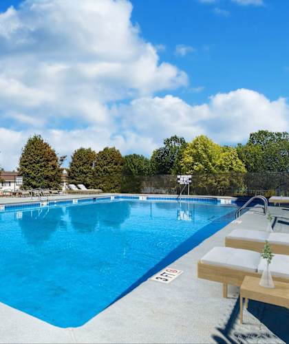 Spartanburg, SC, Pet-Friendly Townhomes - Reserve At Hillcrest - An Outdoor Swimming Pool Surrounded By A Spacious Sundeck With Lounge Chairs, Patio Tables With Umbrellas, And Green Trees.