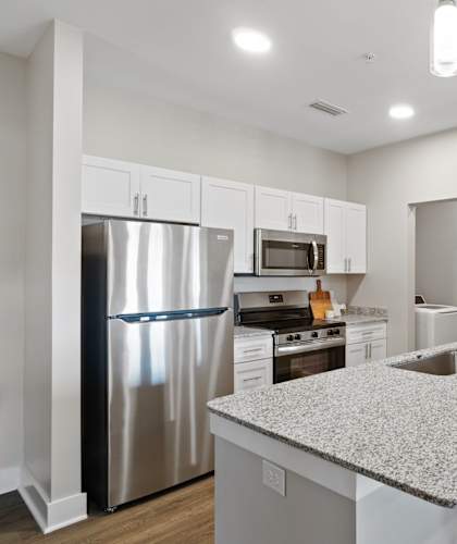 A kitchen with a granite countertop and stainless steel appliances.